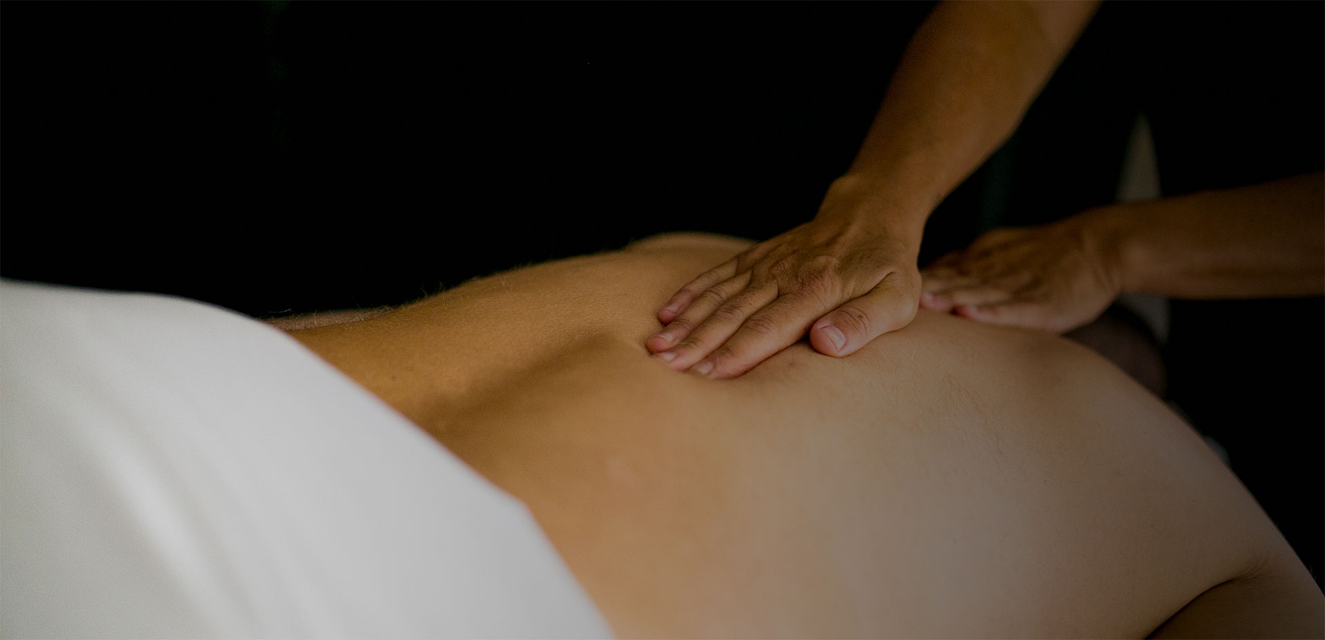 A member of the NHI Massage Clinic giving a back massage to a person lying in a massage table
