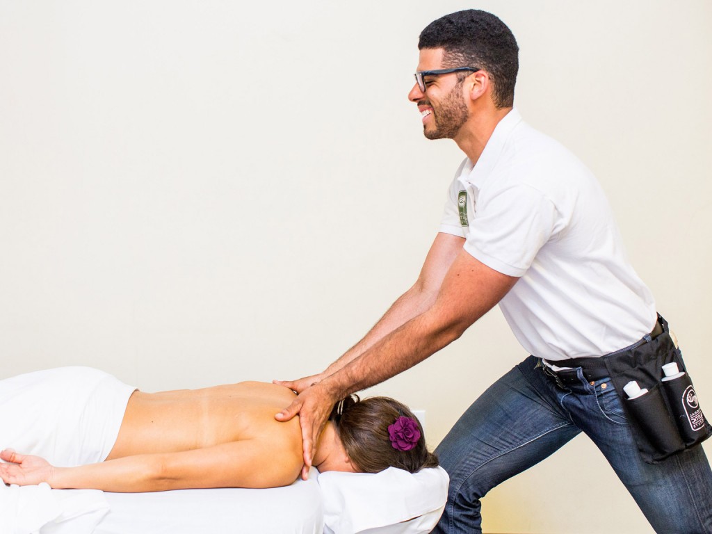 A member of the NHI Massage School giving a neck massage to a person lying in a massage table